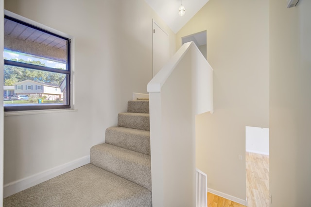 stairs featuring wood-type flooring and lofted ceiling