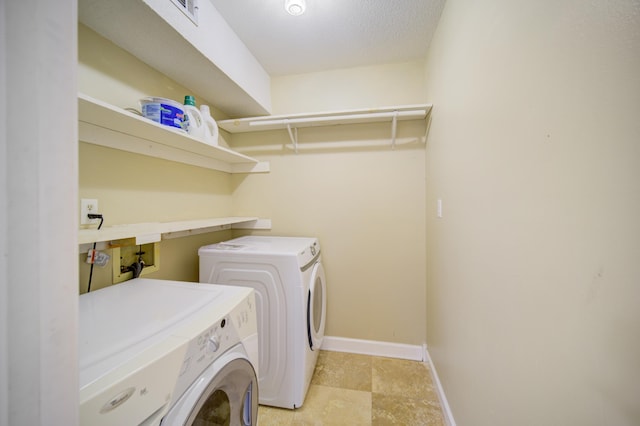 laundry area featuring washing machine and clothes dryer and a textured ceiling