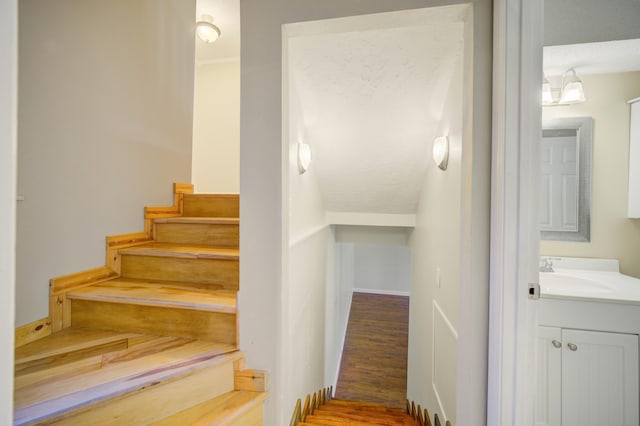 stairs with hardwood / wood-style floors, a textured ceiling, and sink