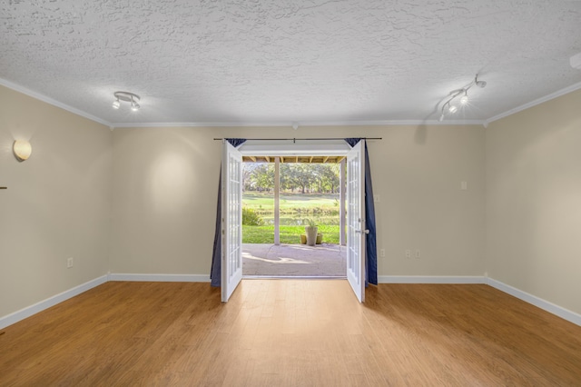 empty room with a textured ceiling, light hardwood / wood-style floors, and crown molding