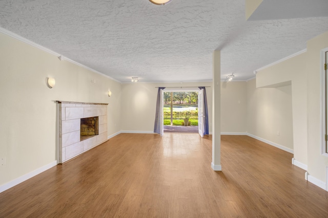 unfurnished living room featuring a fireplace, crown molding, hardwood / wood-style floors, and a textured ceiling