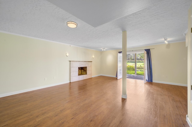 unfurnished living room with a fireplace, crown molding, hardwood / wood-style floors, and a textured ceiling