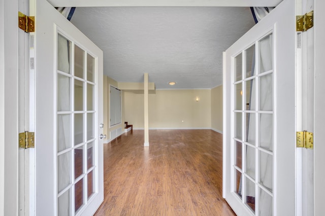 unfurnished room featuring wood-type flooring, a textured ceiling, and french doors