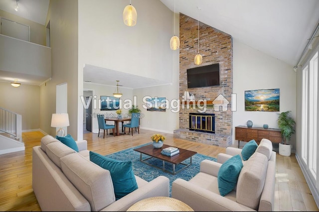 living area featuring baseboards, a brick fireplace, wood finished floors, and stairs