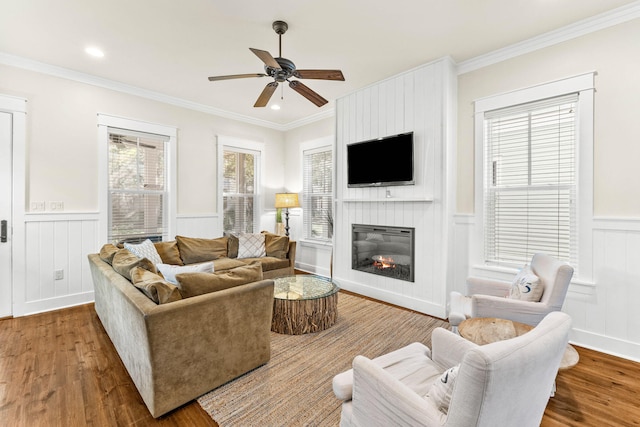 living room featuring a fireplace, hardwood / wood-style flooring, ceiling fan, and ornamental molding