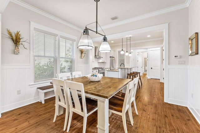 dining room with a healthy amount of sunlight, sink, wood-type flooring, and ornamental molding