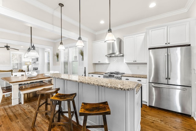 kitchen with white cabinets, appliances with stainless steel finishes, a wealth of natural light, and wall chimney range hood