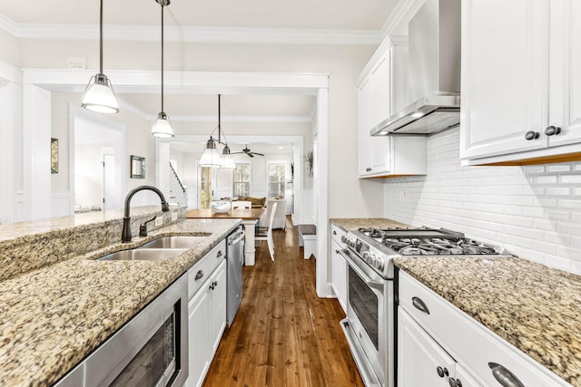 kitchen with white cabinetry, wall chimney range hood, dark hardwood / wood-style floors, decorative light fixtures, and appliances with stainless steel finishes