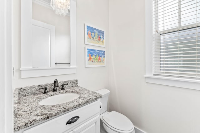 bathroom with crown molding, an inviting chandelier, vanity, and toilet