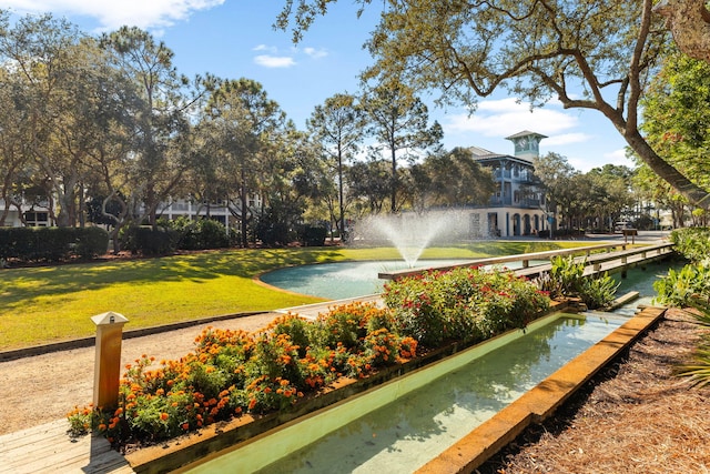 view of property's community with a lawn and a water view