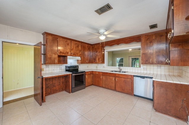 kitchen featuring stainless steel dishwasher, tile counters, electric range, ceiling fan, and sink