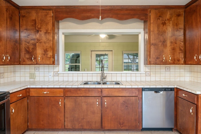 kitchen featuring stainless steel dishwasher, light tile patterned floors, tasteful backsplash, ceiling fan, and sink