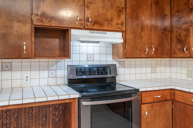 kitchen with stainless steel electric range oven, decorative backsplash, and tile counters