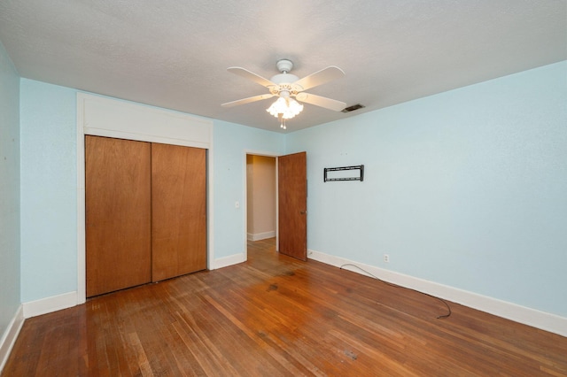 unfurnished bedroom featuring ceiling fan, hardwood / wood-style floors, a closet, and a textured ceiling