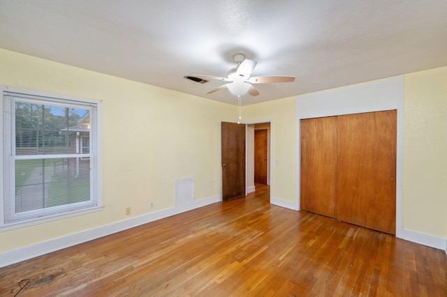 unfurnished bedroom with hardwood / wood-style flooring, ceiling fan, and a closet