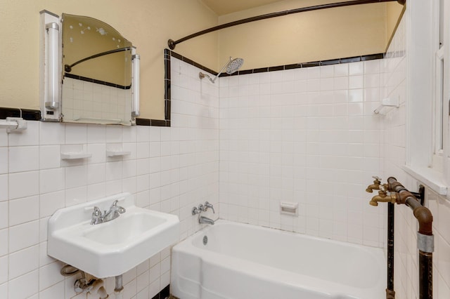 bathroom with tile walls, tiled shower / bath, and sink