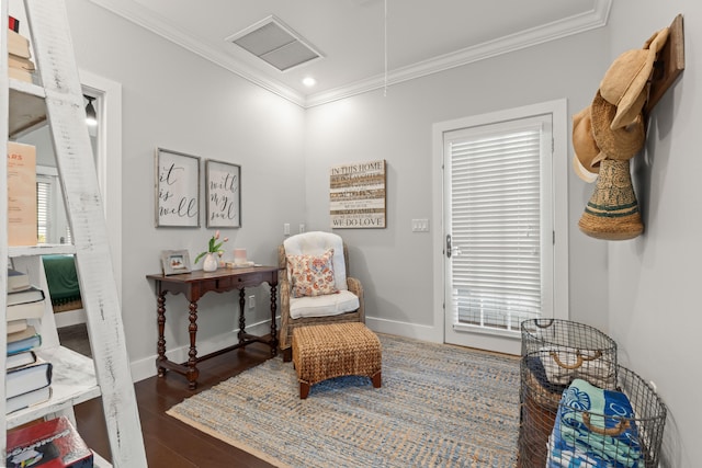 sitting room with ornamental molding and dark wood-type flooring