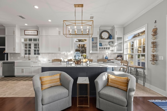 kitchen with white cabinetry, tasteful backsplash, light hardwood / wood-style flooring, crown molding, and decorative light fixtures