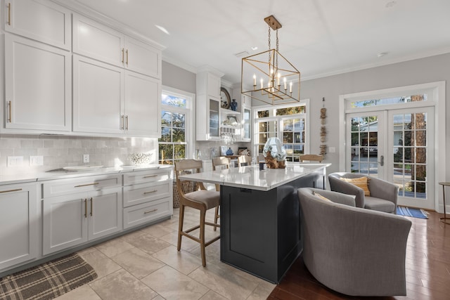 kitchen featuring a breakfast bar area, white cabinetry, french doors, and a center island