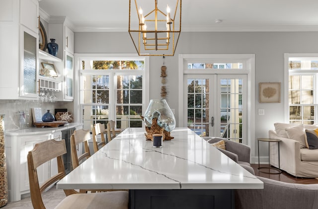 dining room featuring french doors, ornamental molding, a healthy amount of sunlight, and hardwood / wood-style floors