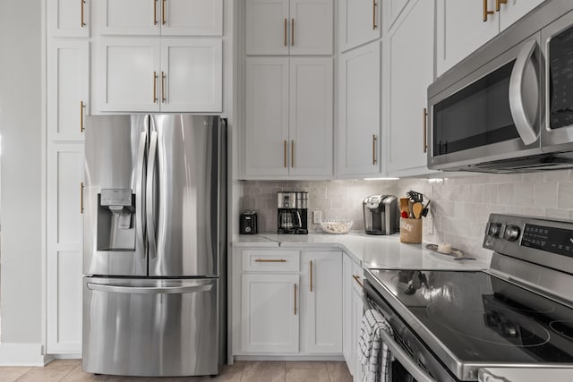 kitchen with white cabinets, light tile patterned flooring, stainless steel appliances, and tasteful backsplash