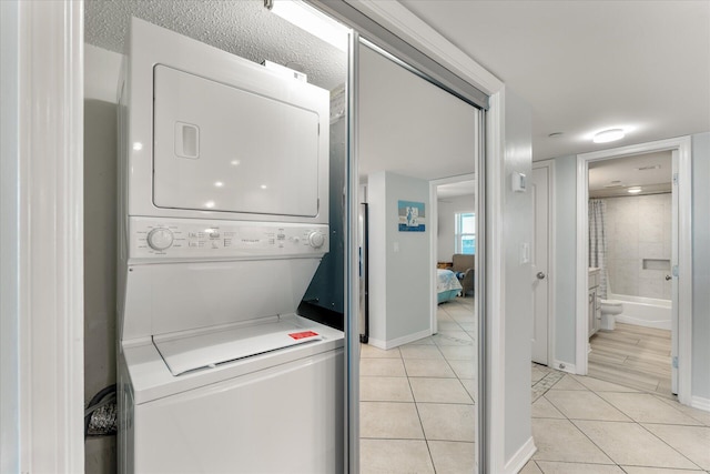 clothes washing area with light tile patterned floors and stacked washer / drying machine