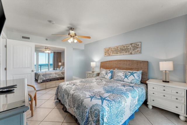 bedroom with access to exterior, ceiling fan, light tile patterned flooring, and a textured ceiling