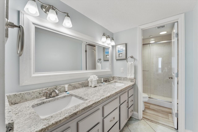 bathroom featuring vanity, hardwood / wood-style flooring, toilet, a textured ceiling, and an enclosed shower