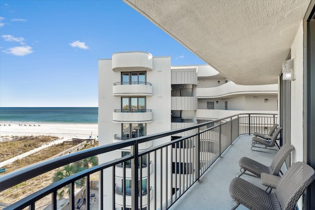 balcony with a water view and a view of the beach