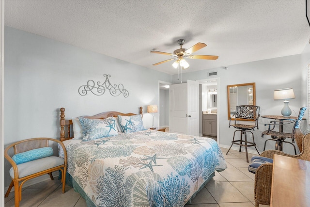 bedroom with ceiling fan, light tile patterned flooring, ensuite bathroom, and a textured ceiling