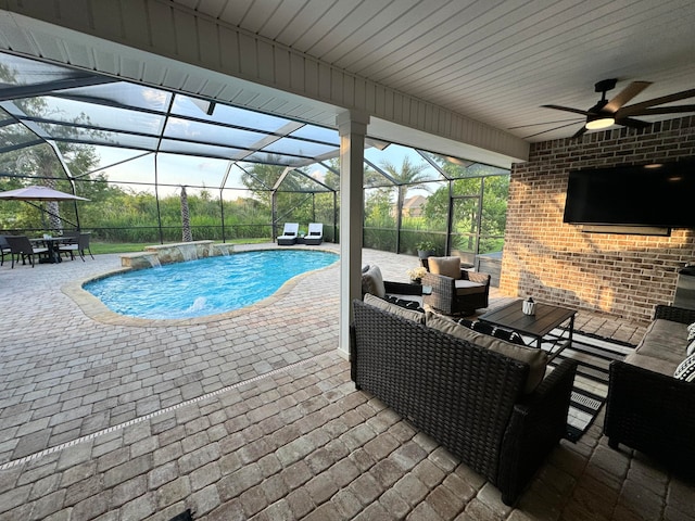 view of pool featuring outdoor lounge area, pool water feature, ceiling fan, glass enclosure, and a patio