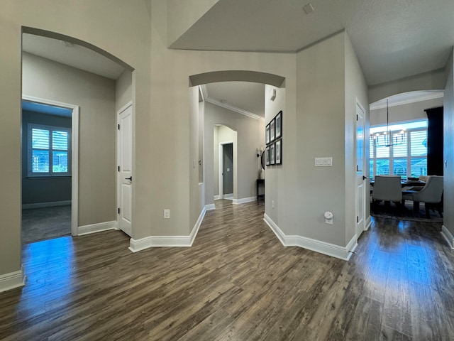 hallway featuring dark hardwood / wood-style flooring, ornamental molding, and a notable chandelier