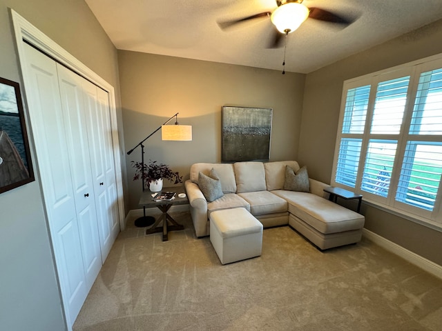 living room with a textured ceiling, ceiling fan, and light carpet