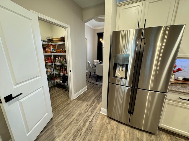 kitchen featuring cream cabinets, ornamental molding, stainless steel refrigerator with ice dispenser, and light hardwood / wood-style flooring