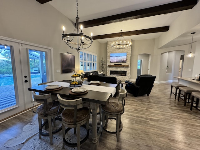 624 Tournament Ln, Freeport, FL 32439 - dining space featuring a chandelier, arched walkways, wood finished floors, a stone fireplace, and beamed ceiling