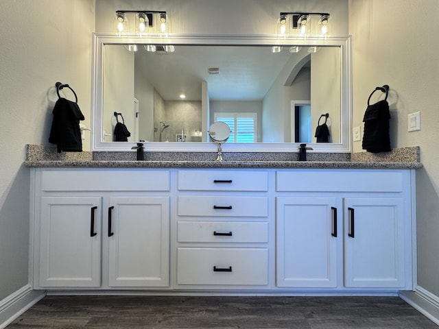 624 Tournament Ln, Freeport, FL 32439 - full bathroom featuring double vanity, a shower with shower door, wood finished floors, and baseboards