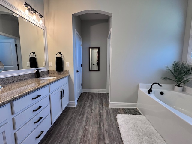 bathroom with hardwood / wood-style floors, vanity, and a tub