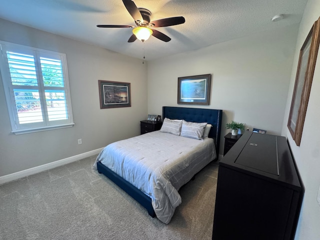 carpeted bedroom featuring ceiling fan and a textured ceiling