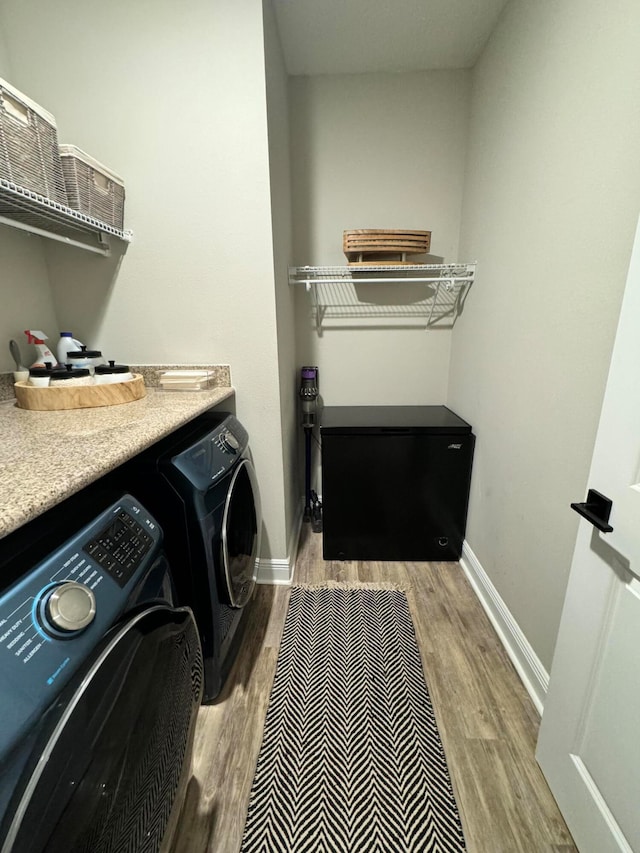 laundry room featuring washing machine and dryer and light hardwood / wood-style flooring