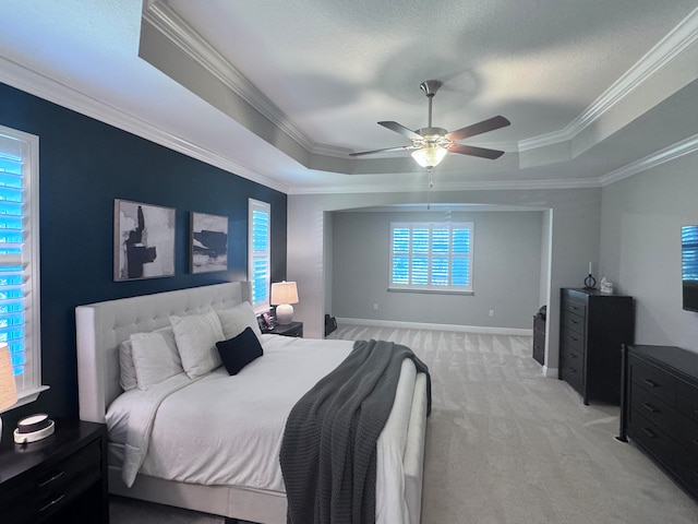 carpeted bedroom with a raised ceiling, ceiling fan, and crown molding