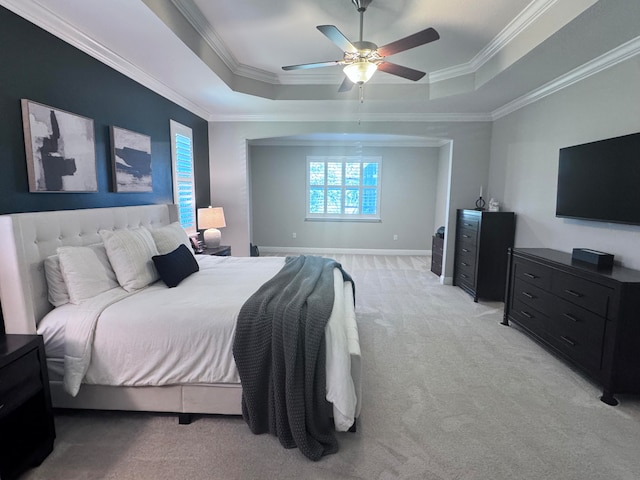 carpeted bedroom featuring a tray ceiling, ceiling fan, and crown molding