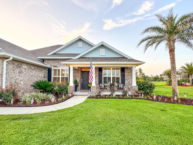 624 Tournament Ln, Freeport, FL 32439 - craftsman-style house featuring brick siding, covered porch, a yard, and roof with shingles