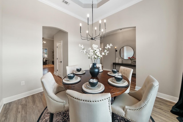 624 Tournament Ln, Freeport, FL 32439 - dining room featuring wood finished floors, arched walkways, crown molding, a chandelier, and baseboards