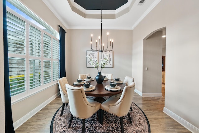624 Tournament Ln, Freeport, FL 32439 - dining space with arched walkways, a raised ceiling, wood finished floors, a chandelier, and baseboards