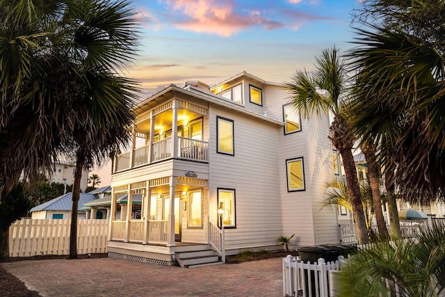 back house at dusk with a balcony and a patio area