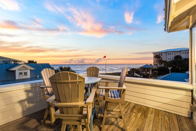 deck at dusk featuring a water view