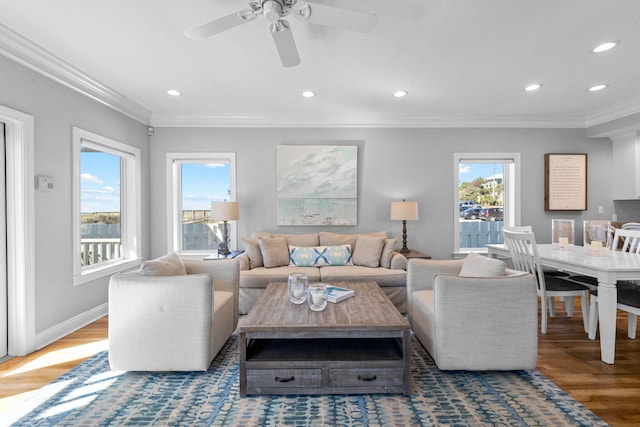 living room with ornamental molding, dark wood-type flooring, ceiling fan, and a healthy amount of sunlight