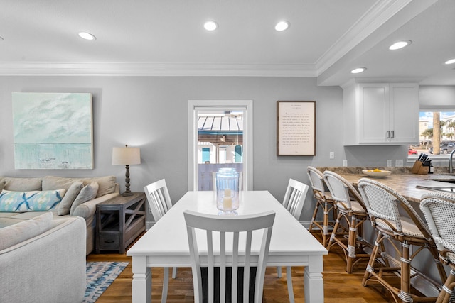 dining space featuring wood-type flooring and crown molding