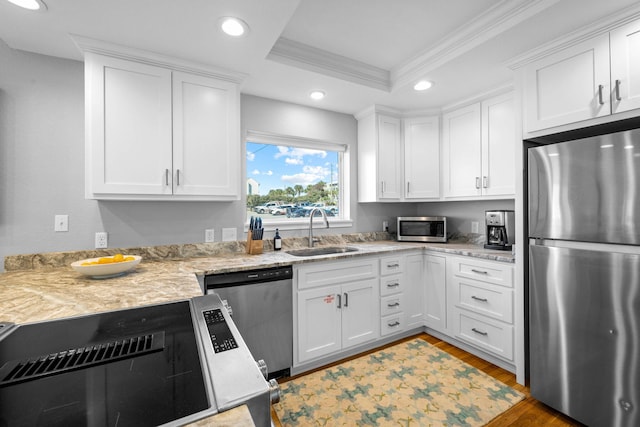 kitchen featuring stainless steel appliances, white cabinetry, ornamental molding, and sink