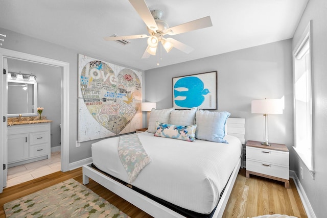 bedroom with multiple windows, connected bathroom, light hardwood / wood-style flooring, and ceiling fan